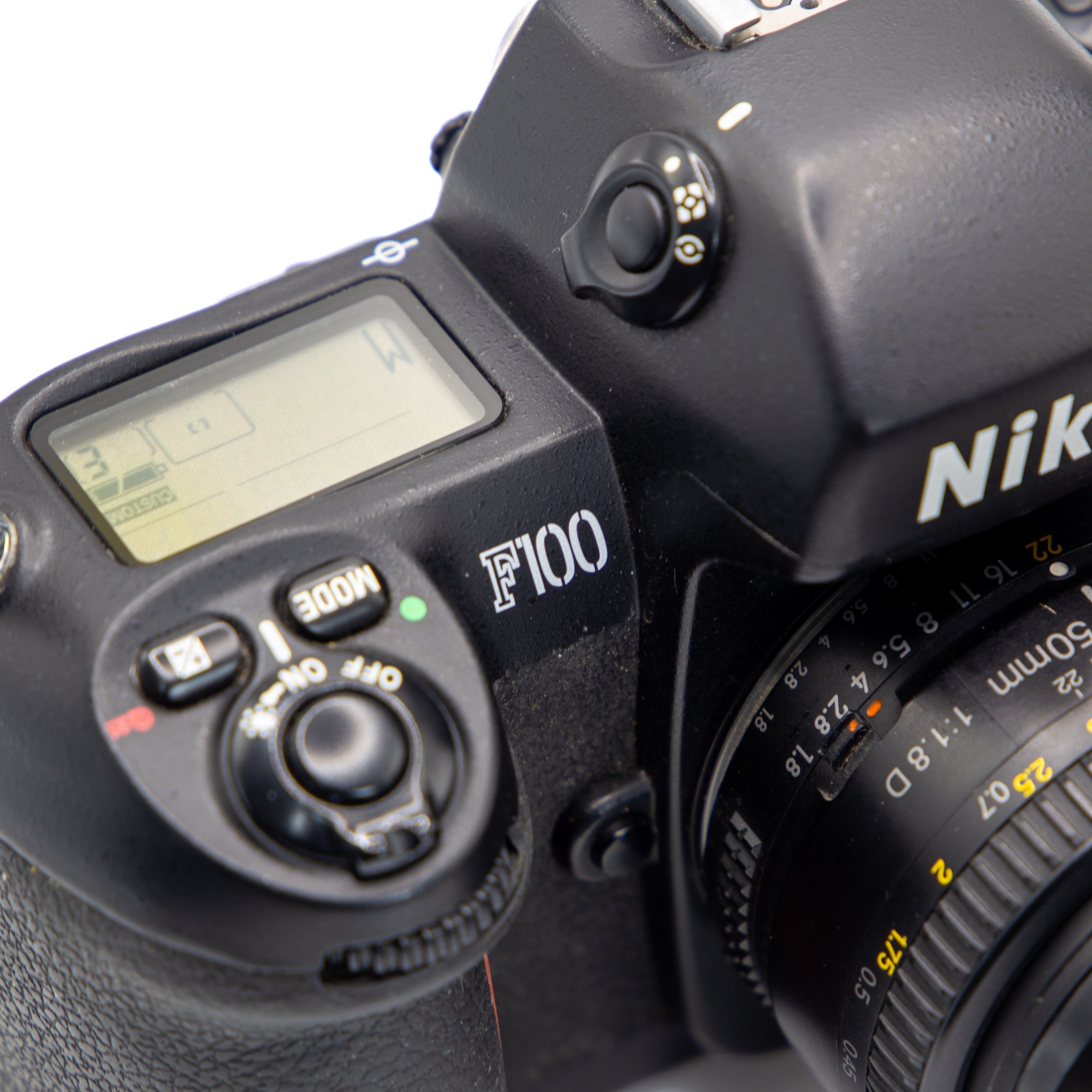 Close-up of a Nikon F100 SLR camera body with a lens attached, showing the top control buttons, LCD screen, and Nikon branding on a white background.