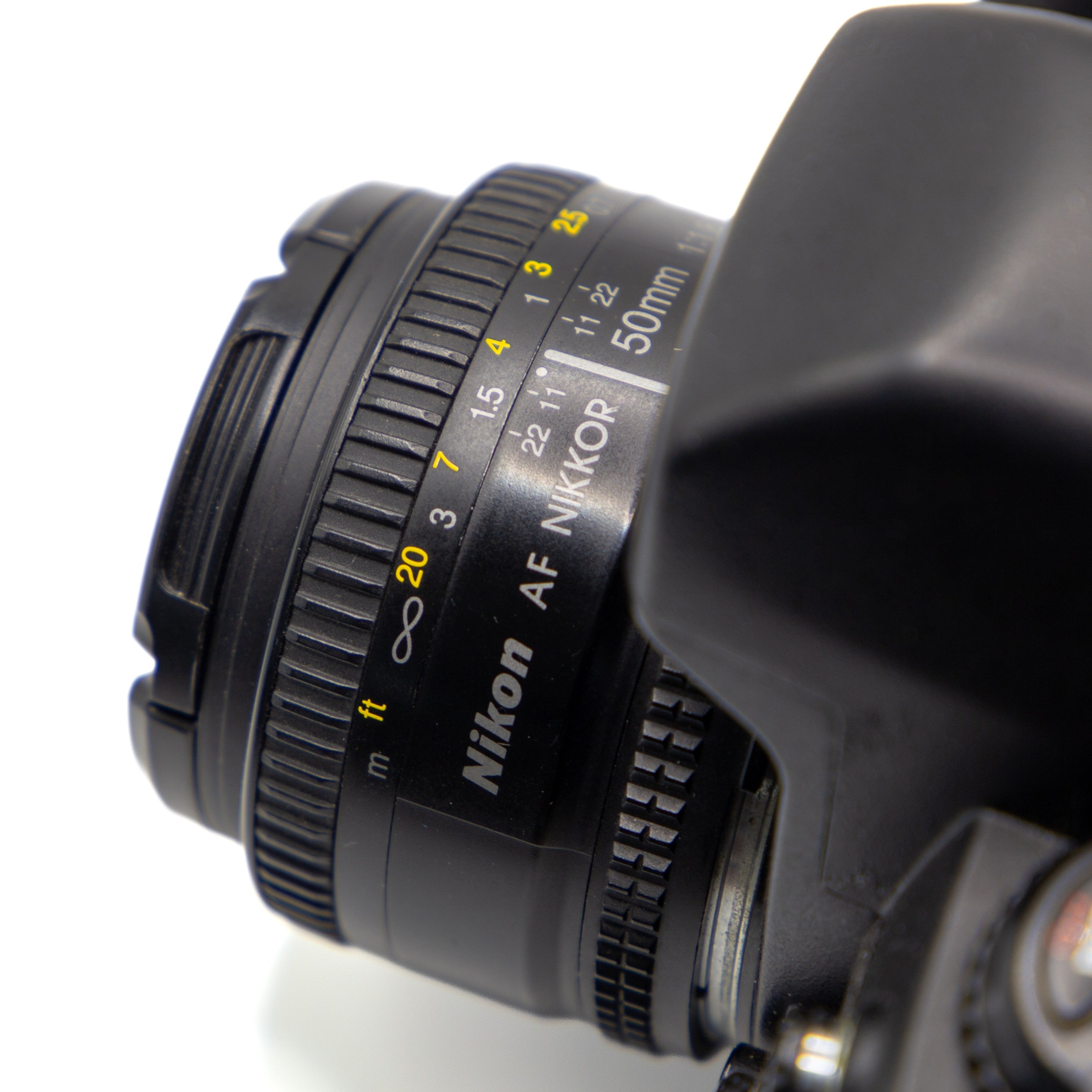 Close-up of a Nikon AF Nikkor 50mm f/1.8D lens attached to a camera body, showing the focus ring, distance scale, and Nikon branding on a white background.