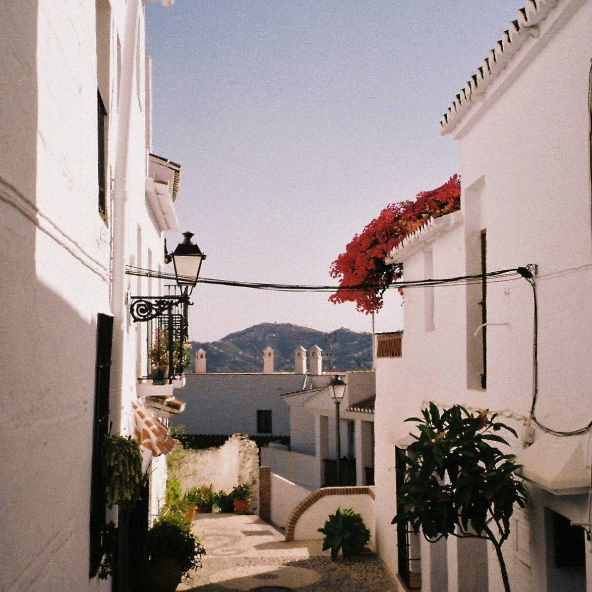 Tiled street with white buildings and mountains in the background
