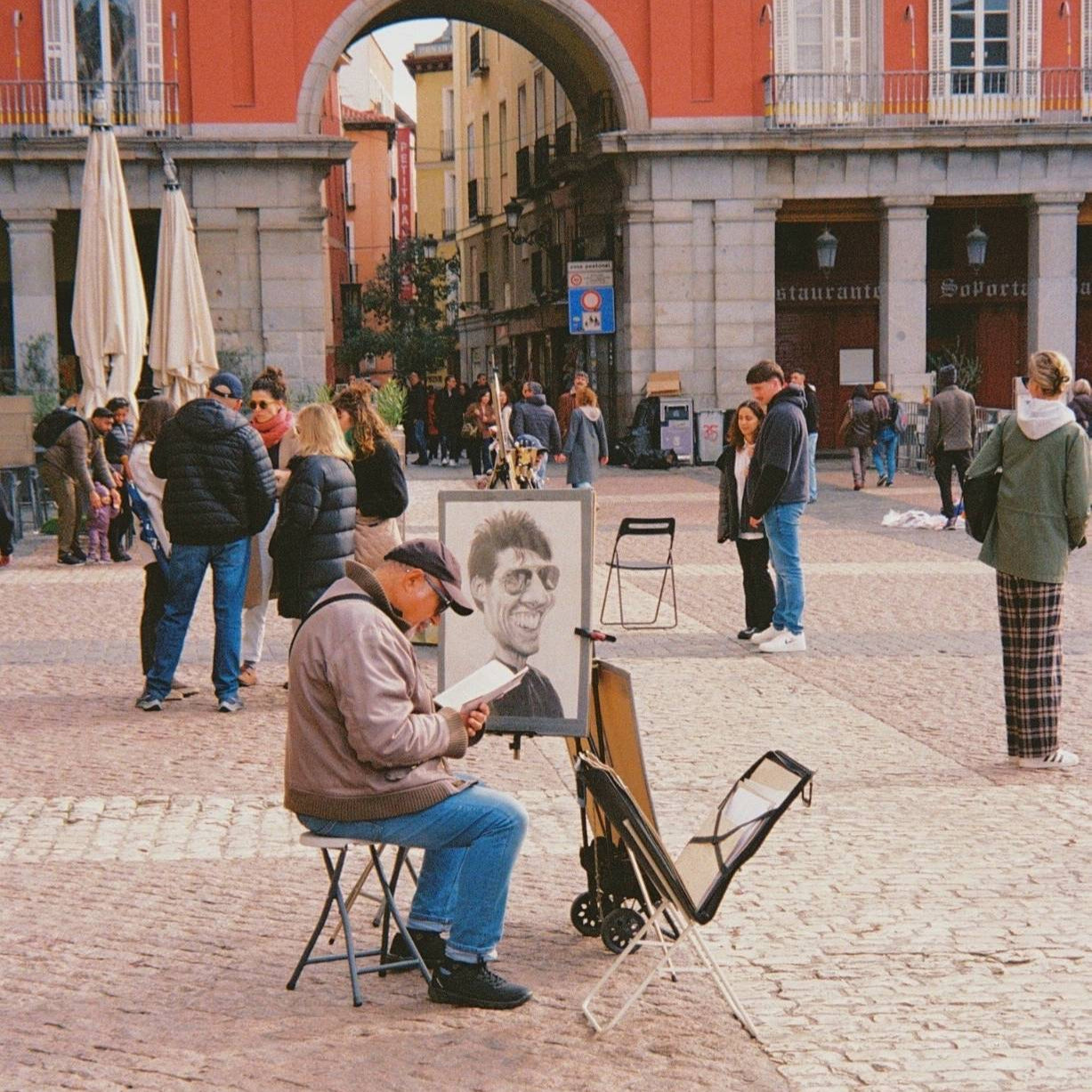 Artist painting on a street corner with people walking by