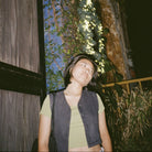 Person standing outdoors with a building and neon sign in the background