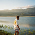 Man standing by a lake with mountains in the background