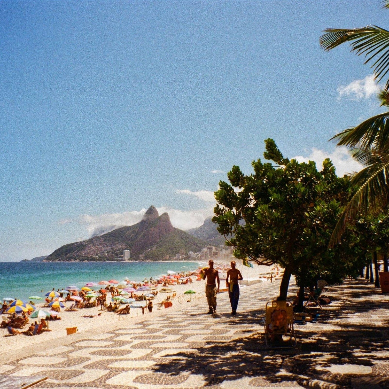 Beach scene with people, umbrellas, and a mountain in the background