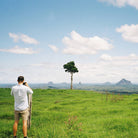 Man taking a photo of a scenic landscape with mountains and a clear sky.